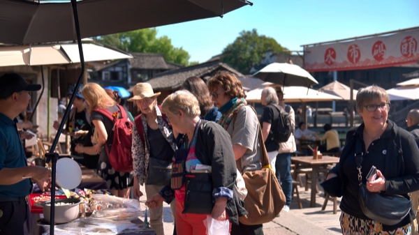 “五一”期间,外国游客正在水乡乌镇街头挑选文创产品。受访者供图